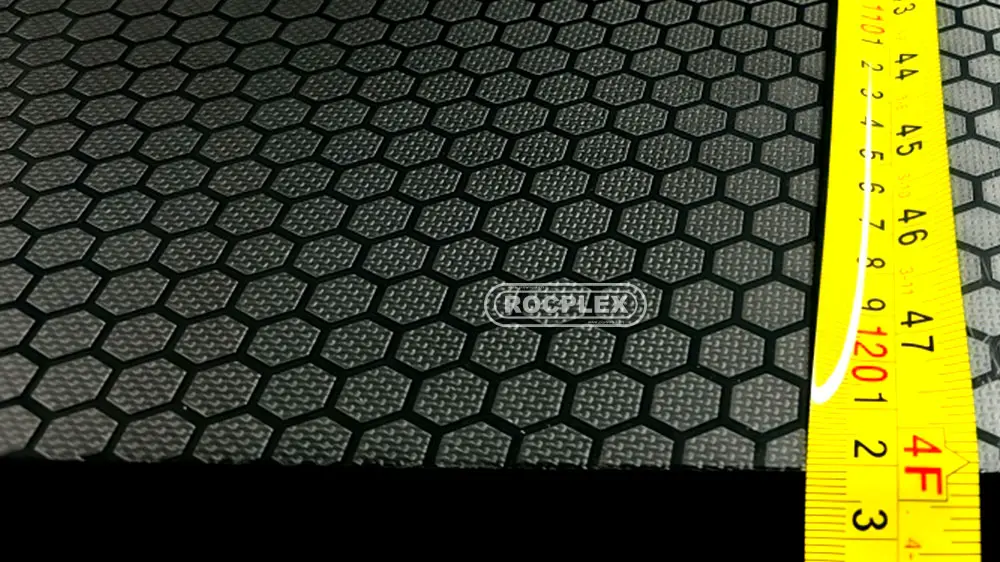 Anti-slip plywood hexagon mesh film surface close-up with measuring tape (ROCPLEX)