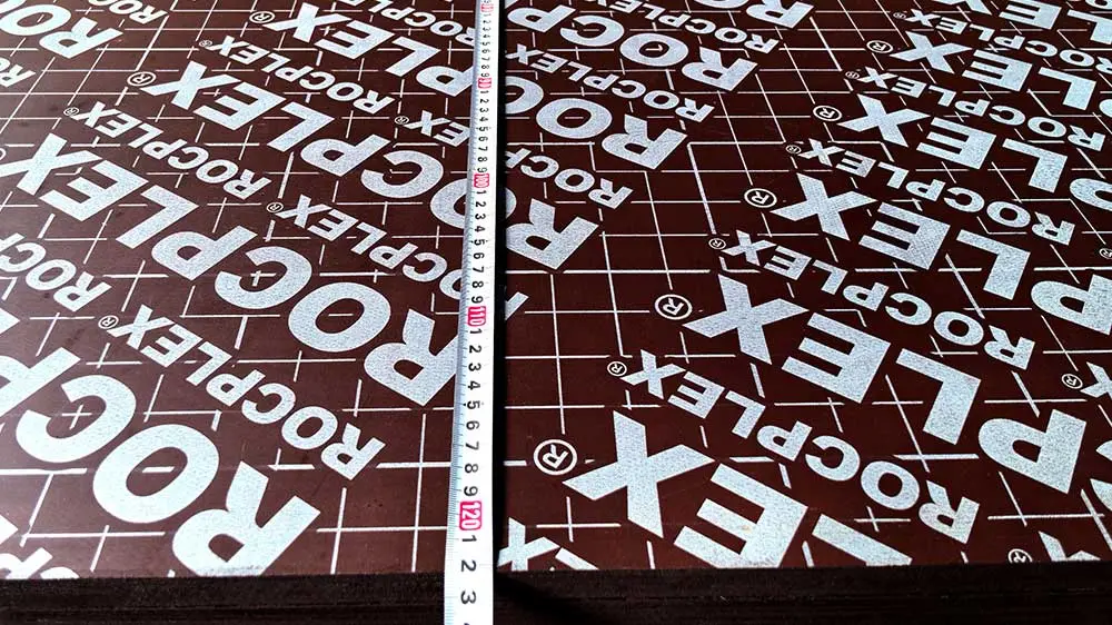 Brown film faced plywood thickness detail – durable formwork plywood panel Close-up of brown film faced plywood with grid phenolic film and thickness measurement for formwork use