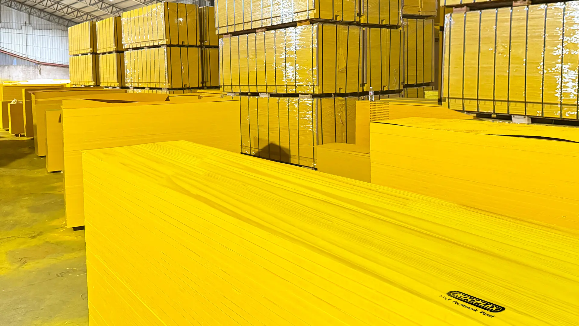 3-ply yellow formwork panel packs in warehouse with export stacking, showing edge protection focus for storage and shipping