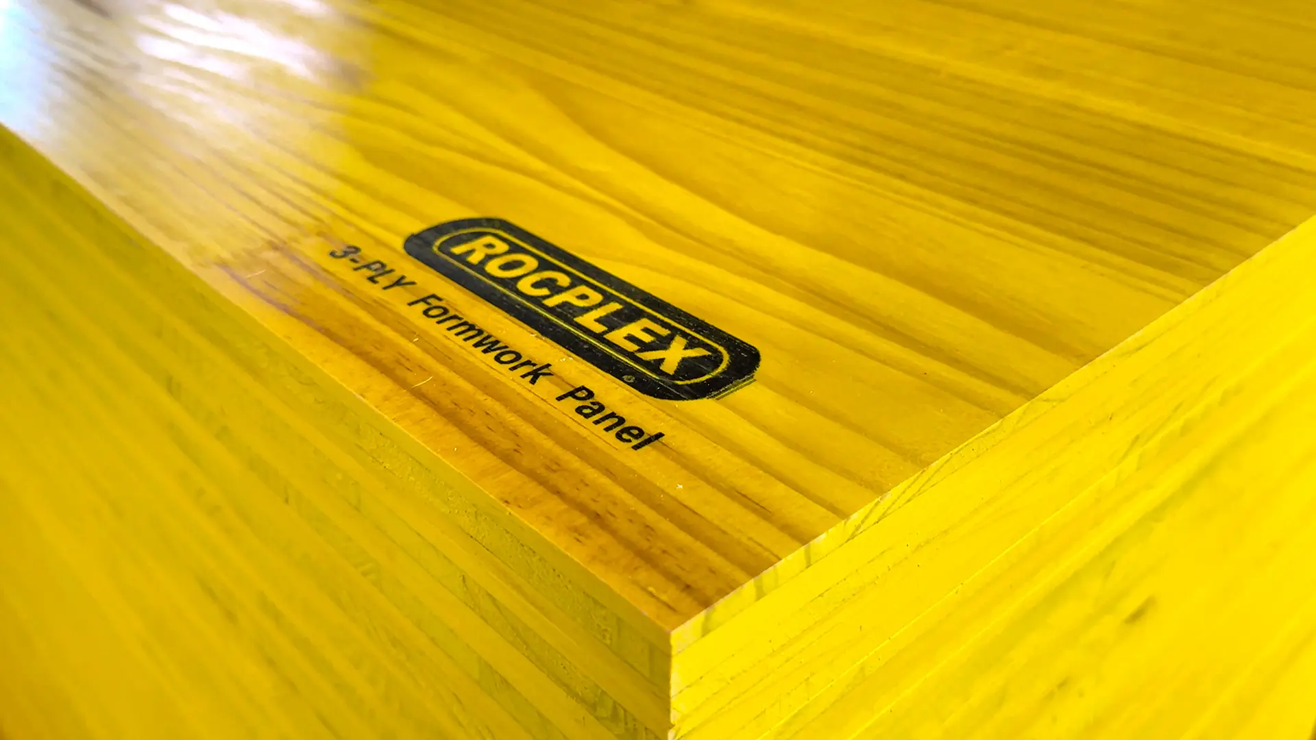 3-ply yellow formwork panel close-up by ROCPLEX showing branded face, smooth yellow coating, and clean panel edges for concrete formwork